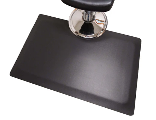 Black rectangular salon and barber mat around the base of a styling chair