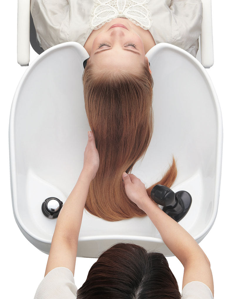 Overhead view of a stylist working through a client’s hair in a Takara Belmont RS shampoo bowl