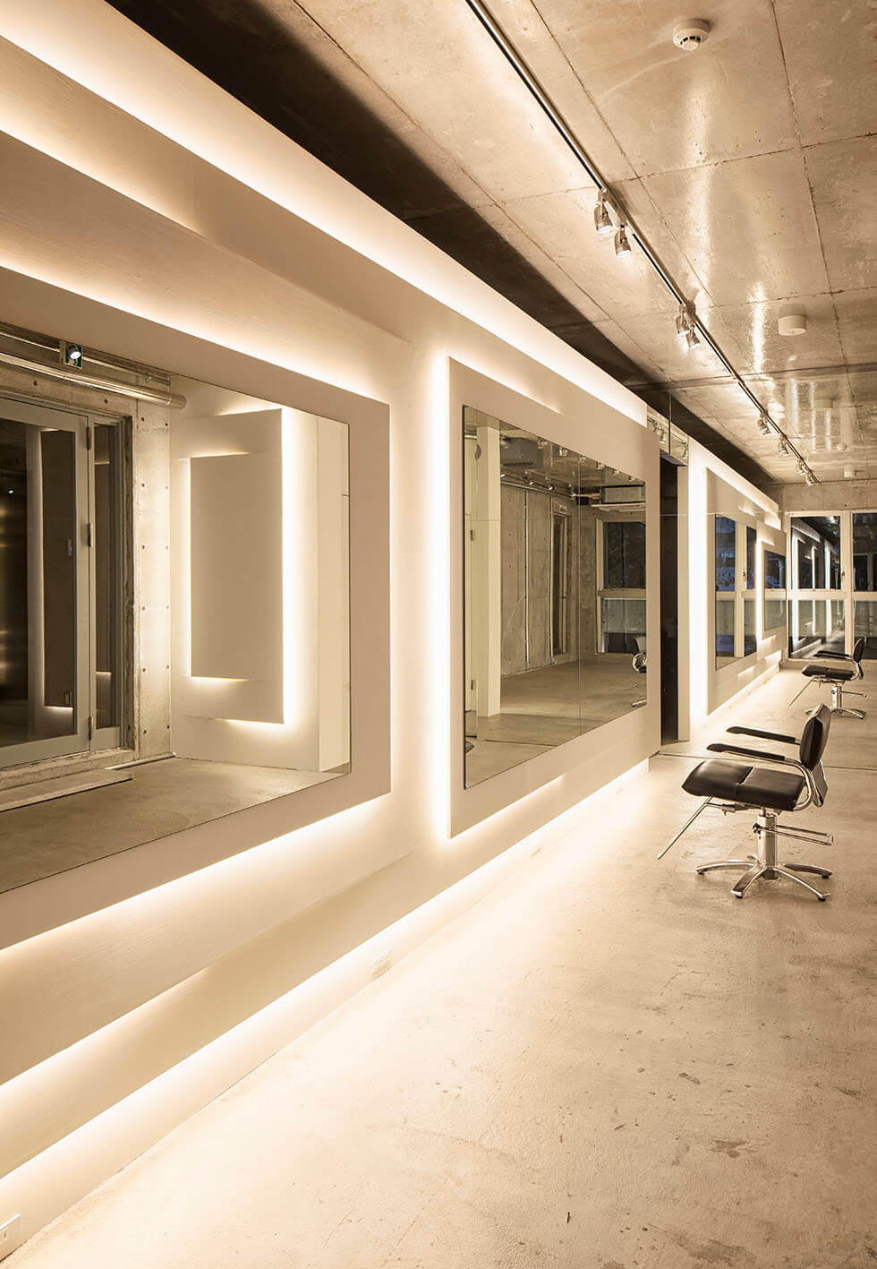 Takara Belmont Captain II styling chairs along illuminated salon mirror stations