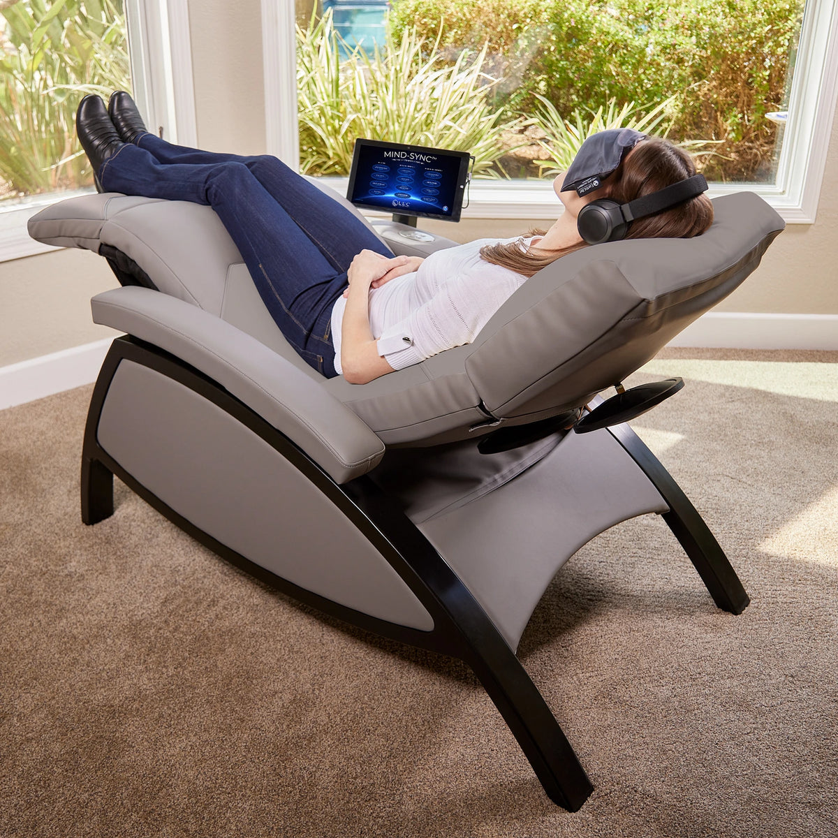 Client reclining on a Mind-Sync 2.0 lounger with headphones beside the display screen