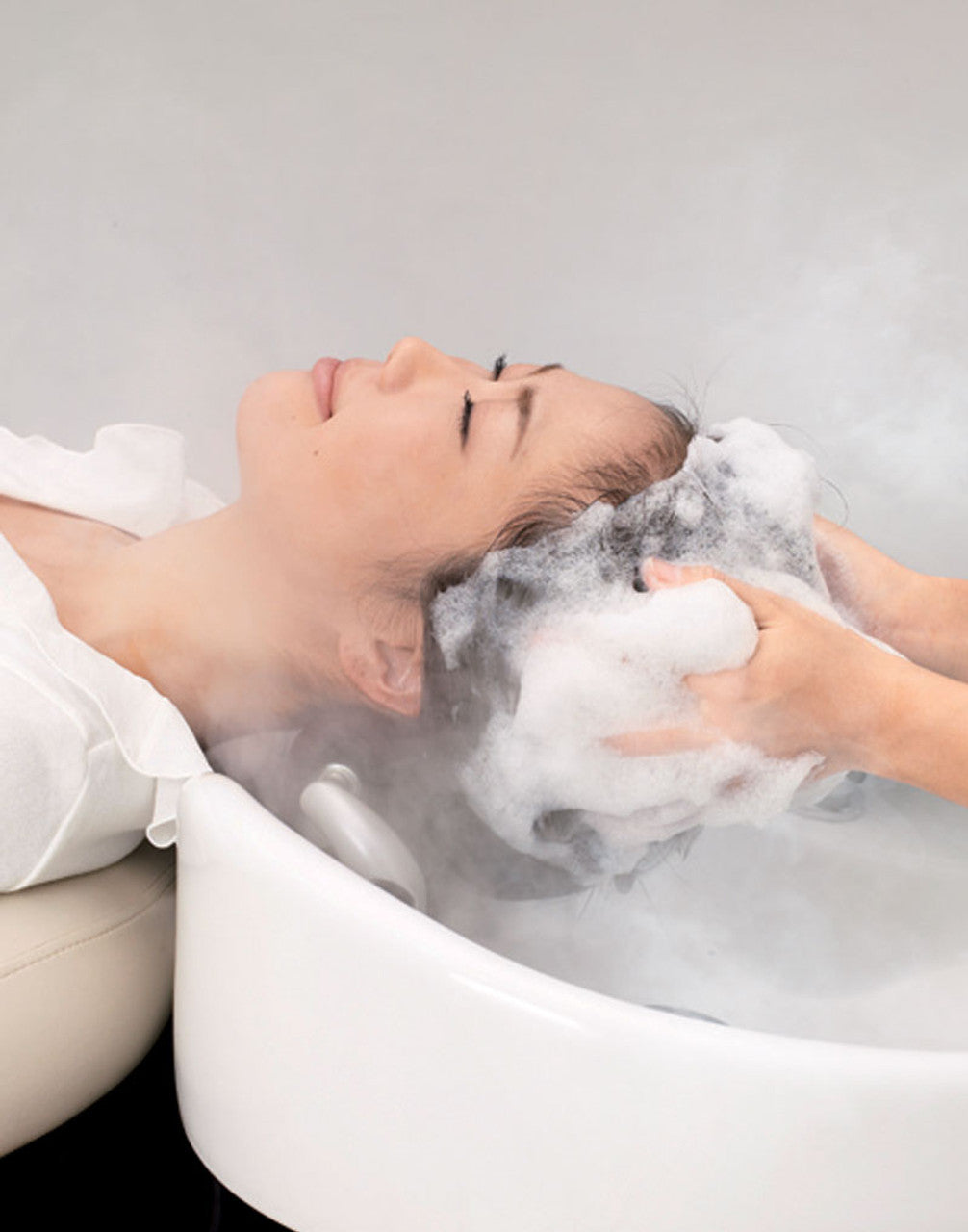 Client receiving a shampoo in a white Takara Belmont YUME Espoir bowl