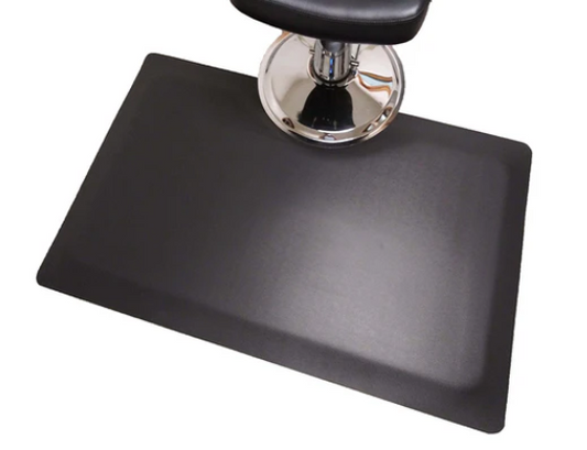 Black rectangular salon and barber mat around the base of a styling chair