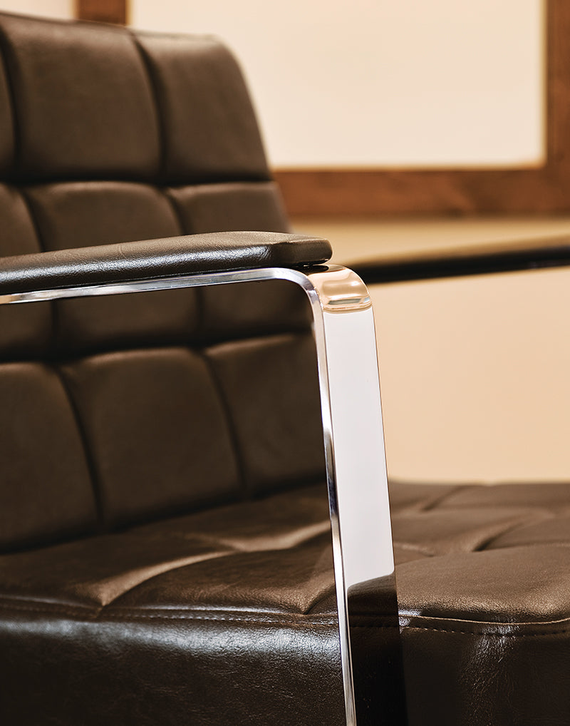 Close-up of brown padded upholstery and chrome armrest on a Takara Belmont Choco chair