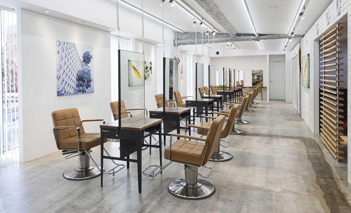 Camel Takara Belmont Choco styling chairs beside black salon workstations