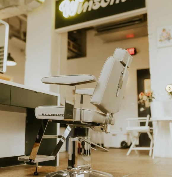 Side and rear view of a Takara Belmont Dainty barber chair with light upholstery in a barbershop