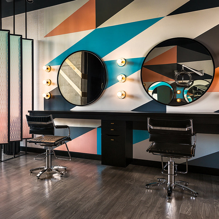 Black Takara Belmont Ghia styling chairs beside round mirrors and colorful wall panels