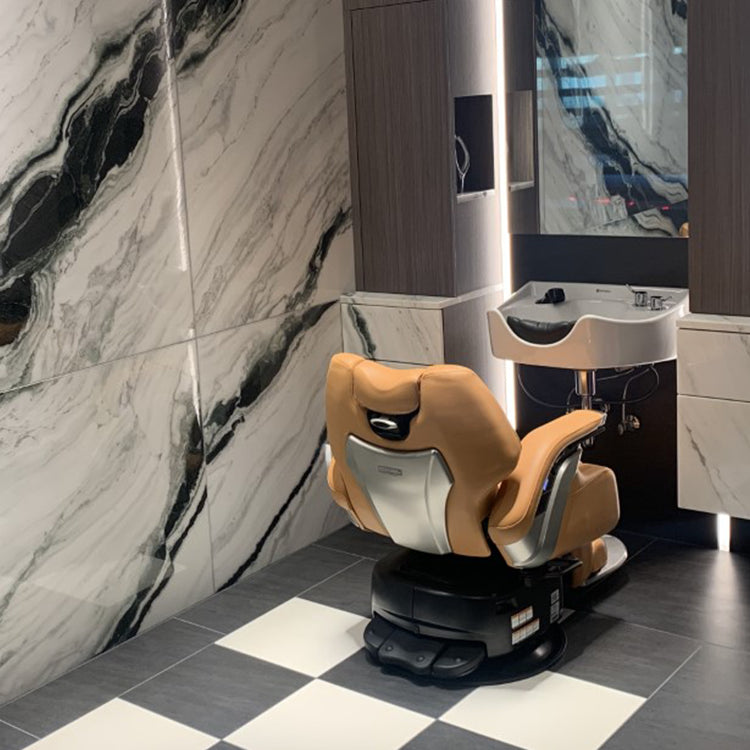 Rear view of a Takara Belmont Legend electric barber chair with tan upholstery at a grooming station