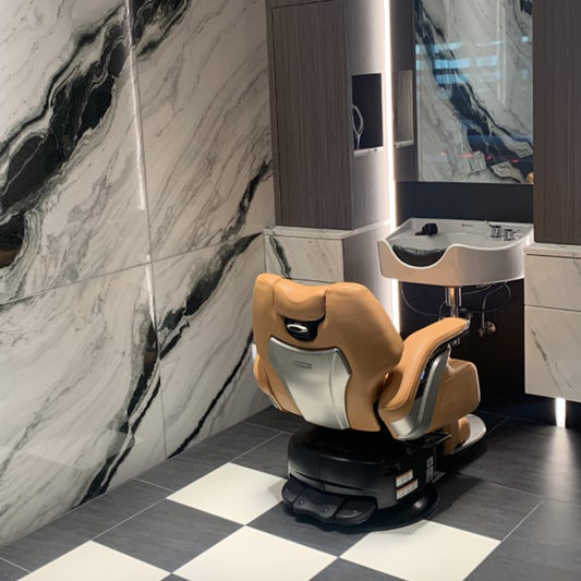 Rear view of a Takara Belmont Legend electric barber chair with tan upholstery at a grooming station