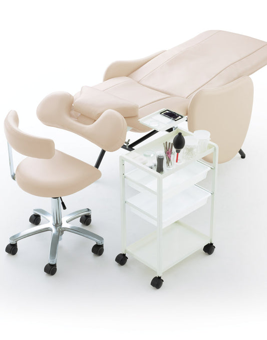 Takara Belmont Riche white treatment wagon beside an ivory bed and technician stool